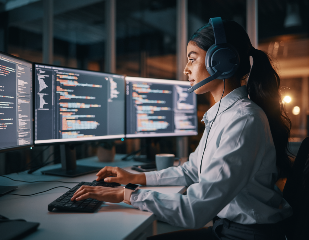 Female DevOps engineer at standing desk, multiple terminals open, Kubernetes dashboard, noise-canceling headphones, smartwatch, focused expression, clean minimalist office