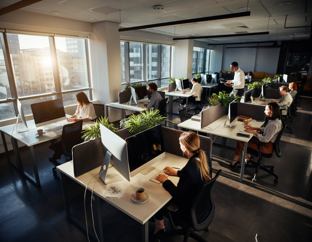 Cozy startup coworking space, exposed brick walls, wooden tables, MacBooks, sticky notes on glass boards, young team brainstorming, warm pendant lights