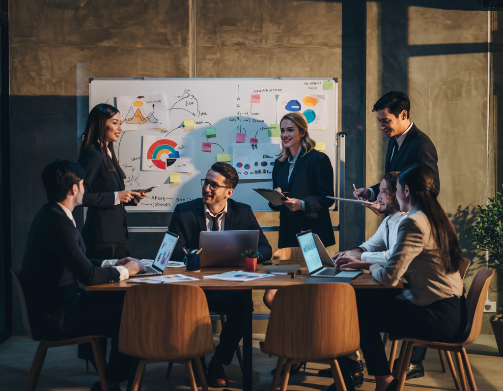 Group of office professionals gathered around a conference table in a modern meeting room, collaborating on business strategies, sharing ideas, and discussing project plans in a corporate environment